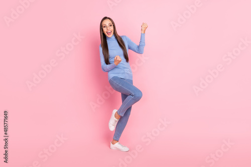Photo of astonished champion lady rejoice win wear specs blue turtleneck jeans sneakers isolated pink color background