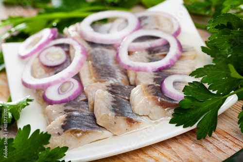 Tasty herring fillet, sliced with onions and parsley. High quality photo