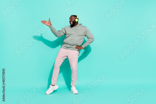 Full length body size view of cheerful attractive guy moving dancing hip hop rhythm pop isolated over bright teal turquoise color background