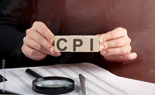 cpi text wooden cube blocks hand holding magnifying glass and chart on table background. photo