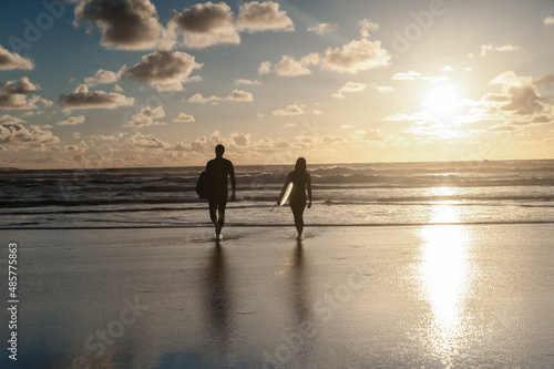 Photography Couple surfing at Constantine Bay at sunset, Cornwall, England, United Kingdom,
