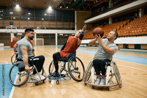 Group of wheelchair-bound players playing basketball match on sports court. © Drazen