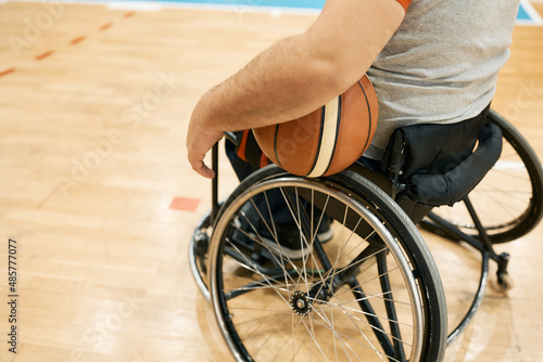 Close-up of handicapped athlete in wheelchair with basketball on the court.