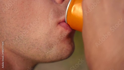 A man drinks from an aluminum orange can.