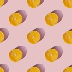 Uniform pattern of dried lemon slices with shadow on a pink background. Flat lay