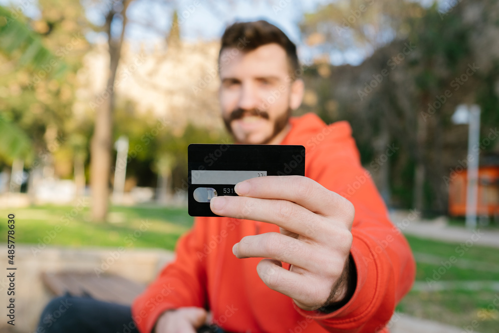 Credit card, a young man posing with a credit card, happiness after a black bank card and online shopping Credit card, a young man posing with a credit card, happiness after a black bank card and online shopping