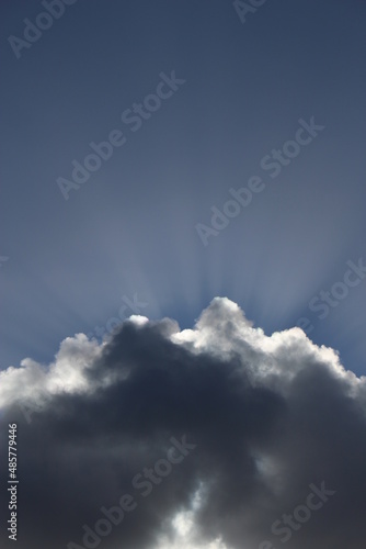 Sun bursting out of a fluffy white cloud. Wallpaper, background or graphic resource concept photo