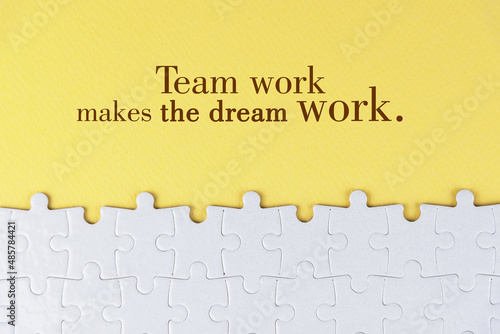Business motivational quote - Team work makes the dream work. On yellow background of white jig saw puzzle missing pieces. Success team work concept.