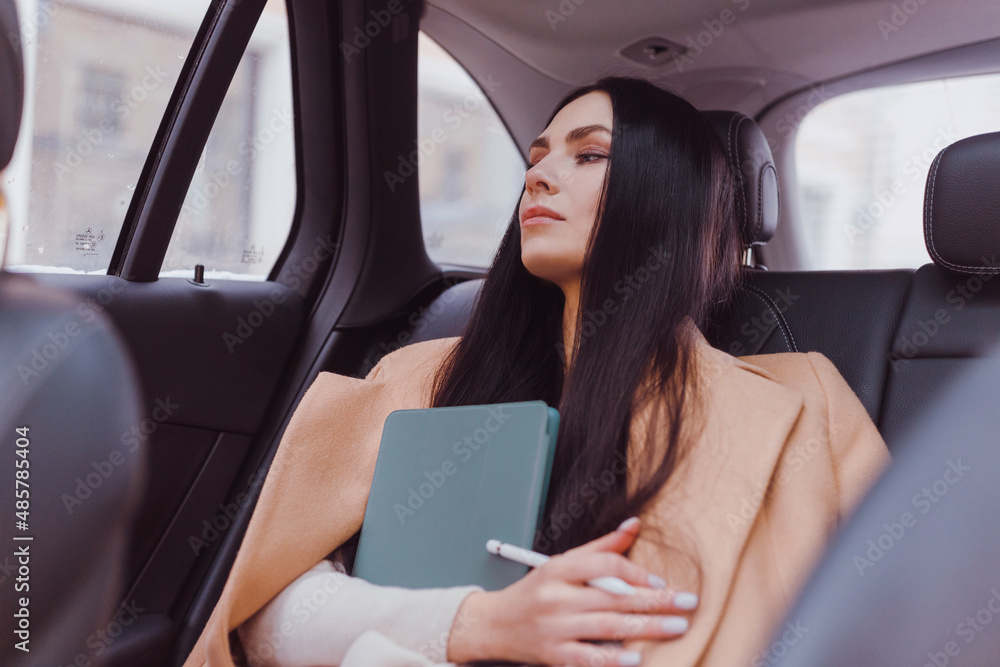 Young european businesswoman portrait inside taxi using tablet.