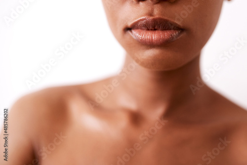 Keep your lips from cracking by moisturising. Closeup shot of a beautiful young woman posing with glossy lips against a white background. photo
