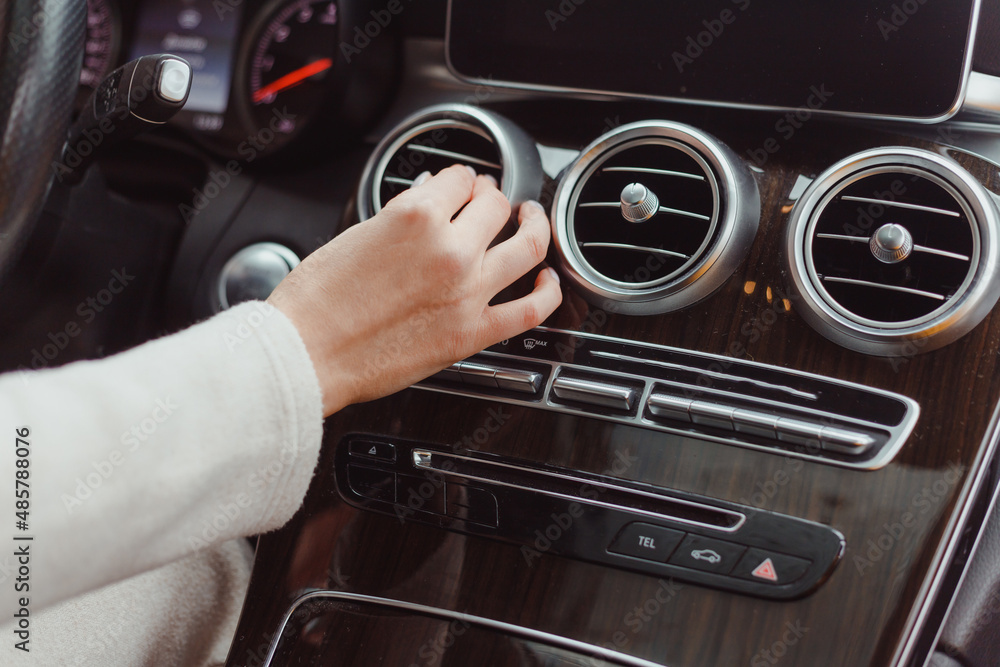 Hand of woman turning on car air condition system,Button on dashboard in car panel,Auto car air condition