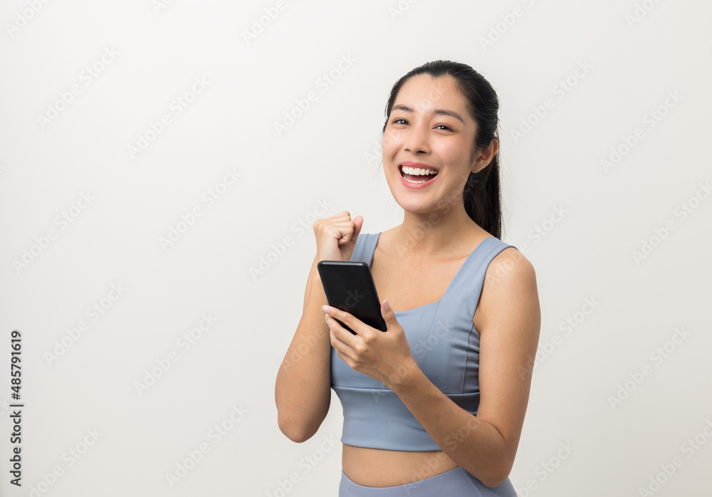 Happy Beautiful young asian sporty woman using smartphone mobile standing on isolated white background. Good shape woman wearing sportswear holding cell phone.