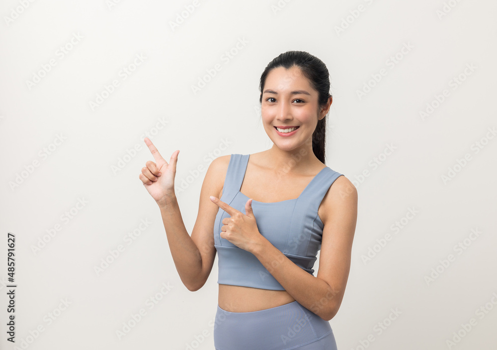 Sexy sporty fitness woman standing and pointing finger to blank space for advertise text. Good shape and healthy female pose on backdrop isolated white background. Sexy sporty fitness woman standing and pointing finger to blank space for advertise text. Good shape and healthy female pose on backdrop isolated white background.