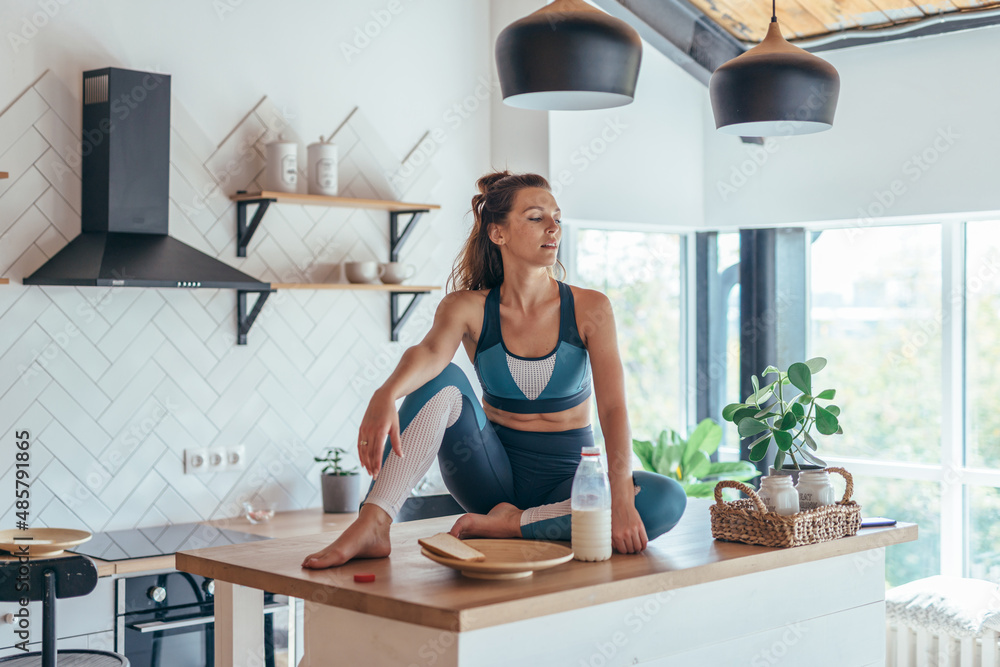 © undrey - Young woman in sports clothes in the kitchen at home