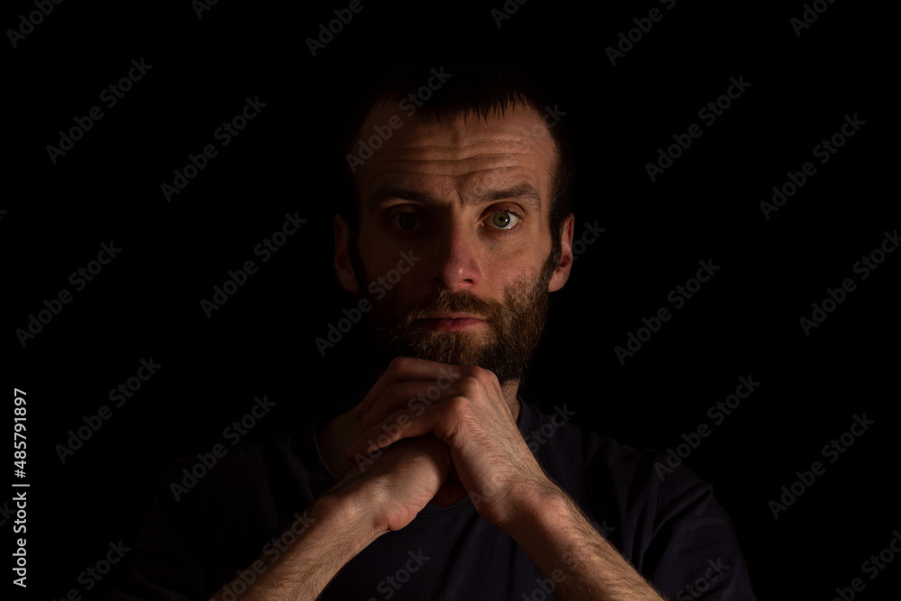 a man on a dark background in a dark T-shirt holds his hands in front of him. place for text a man on a dark background in a dark T-shirt holds his hands in front of him. place for text