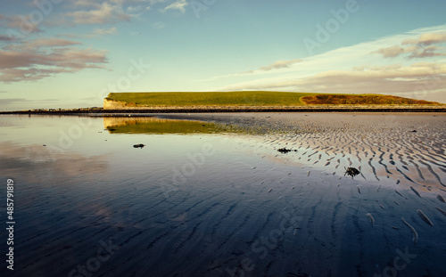 Morning coastal landscape scenery of mountain reflected in water of sandy Silverstrand beach in Galway  Ireland 