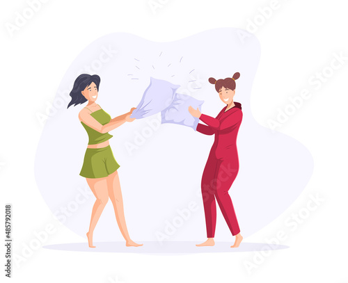 Smiling female friends playing pillow fight having fun together enjoying friendship