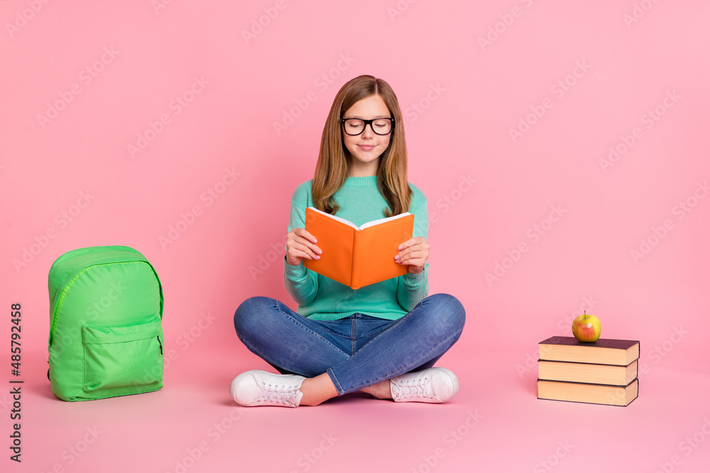 Photo of smart girl wear turquoise sweater holding school supplies reading book isolated pink color background Photo of smart girl wear turquoise sweater holding school supplies reading book isolated pink color background