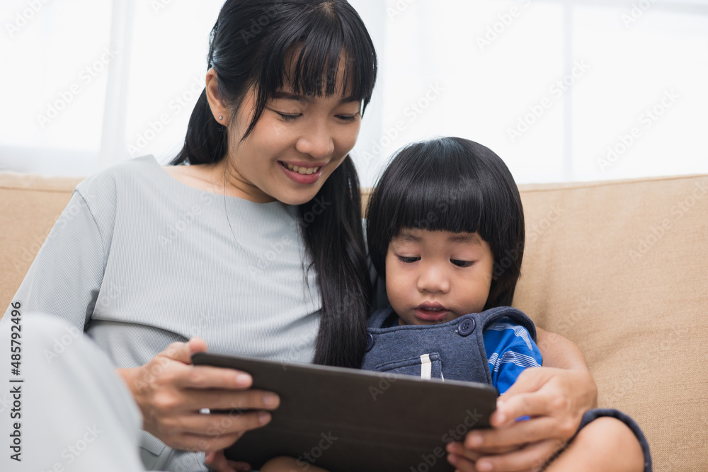Happy asian family mother and son using tablet for education. Little boy watching funny social media. Mom with kid using tablet video call to father. Happy asian family mother and son using tablet for education. Little boy watching funny social media. Mom with kid using tablet video call to father.