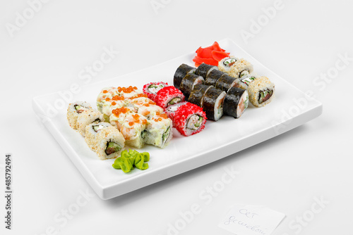 Set of different sushi rolls with rice, fish, cucumbers, wasabi, ginger, caviar and sesame. Large white plate on a white background. Lots of sushi in one dish.