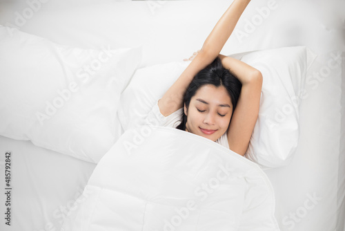 Young woman wake up before lying asleep enjoying healthy in the morning. Beautiful asian woman sleeping well in comfortable cozy fresh bed on soft pillow white linen.