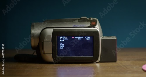 old mini dv camcorder with opened display on wooden table showing the red record screen, nice music video footage or mock up. 