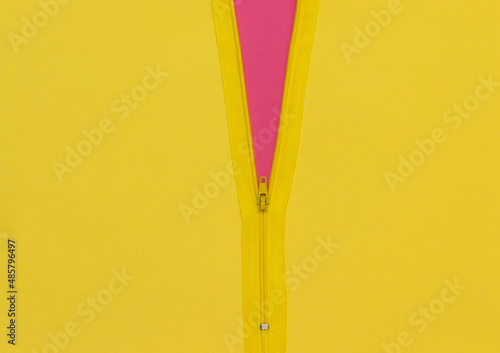 Foto Yellow zipper unzipped half way showing violet color under a yellow background