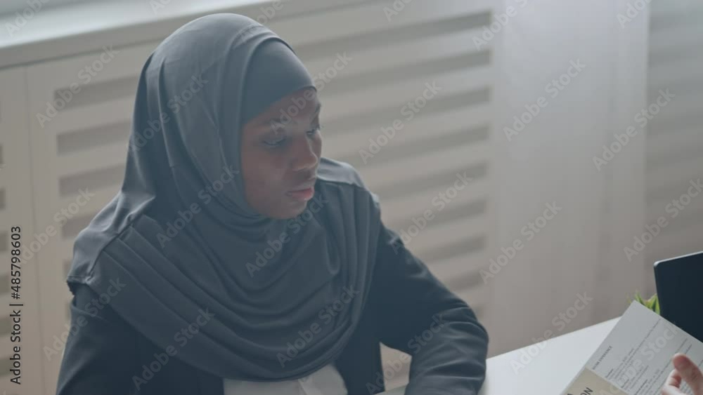 Black woman in hijab attending job interview, male HR manager reading CV Black woman in hijab attending job interview, male HR manager reading CV