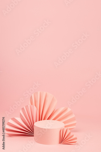 Fashion romance pink scene mockup with single cylinder podium  airy pink origami paper hearts on pastel background  copy space  vertical. Stage template for advertising  presentation cosmetic product.