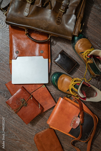 A set of vintage brown leather every day use man accessorys: a briefcase, messenger bag, tramp shoes, a purse, notebook and a notepad with a handmade leather binding, and a laptop. Top view (flat-lay)