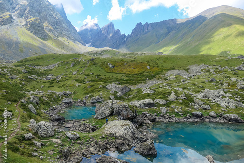 A man enjoying the Colorful Abudelauri mountain lakes in the Greater Caucasus Mountain Range in Georgia,Kazbegi Region. Trekking and outdoor travel.Alpine pastures.Lake Reflection.Green lake © Chris