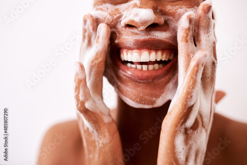 Keeping my skin clean is what keeps it looking good. Studio shot of an unrecognizable woman washing her face against a white background. photo