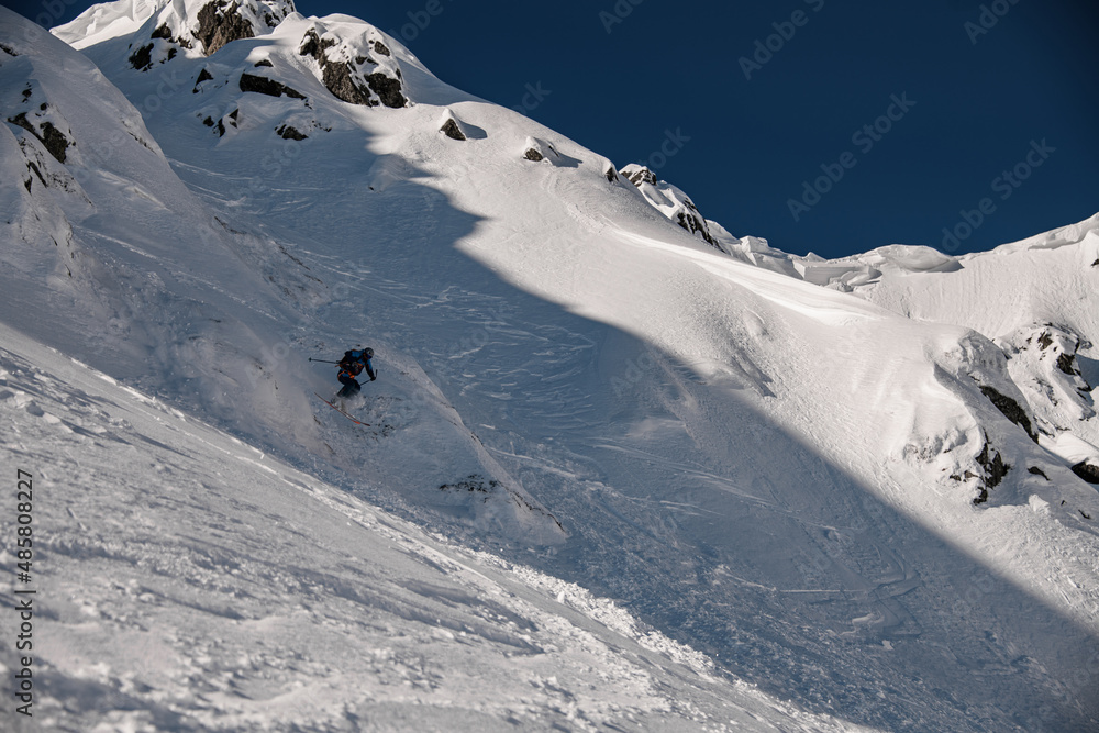 Great view of the rocky snow-covered mountain slope and the skier slides down