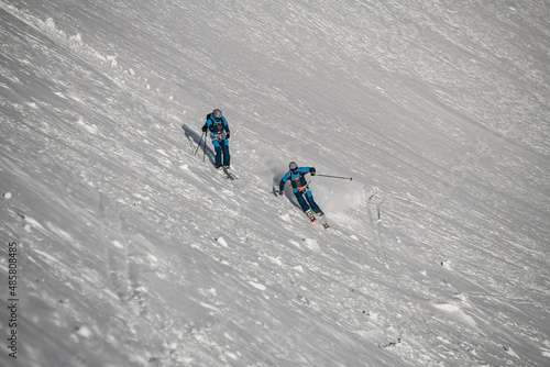 beautiful view of two skiers going down the snowy mountain slope