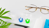 Contact lens kit with lenses, container, glasses and eye drops on a white table with copy space. The concept of proper use of contact and night lenses and their care. Eyecare
