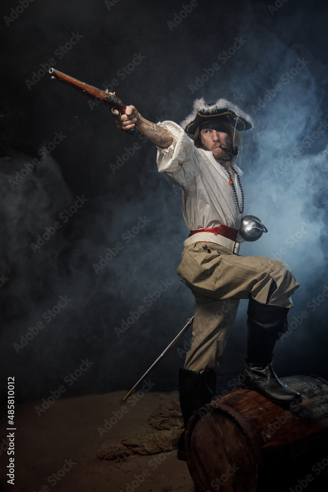 Portrait of pirate filibuster sea robber aiming from old pistol. Concept photo