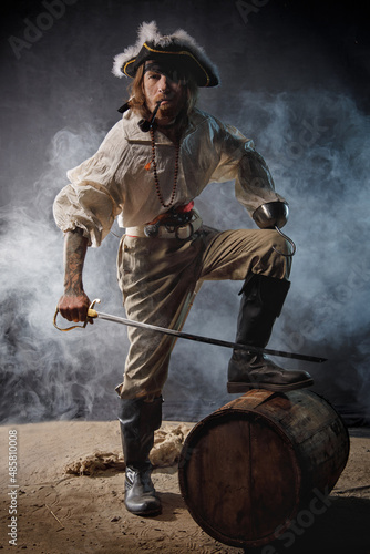 Fotografia Pirate filibuster sea robber in suit with saber is standing next to barrel