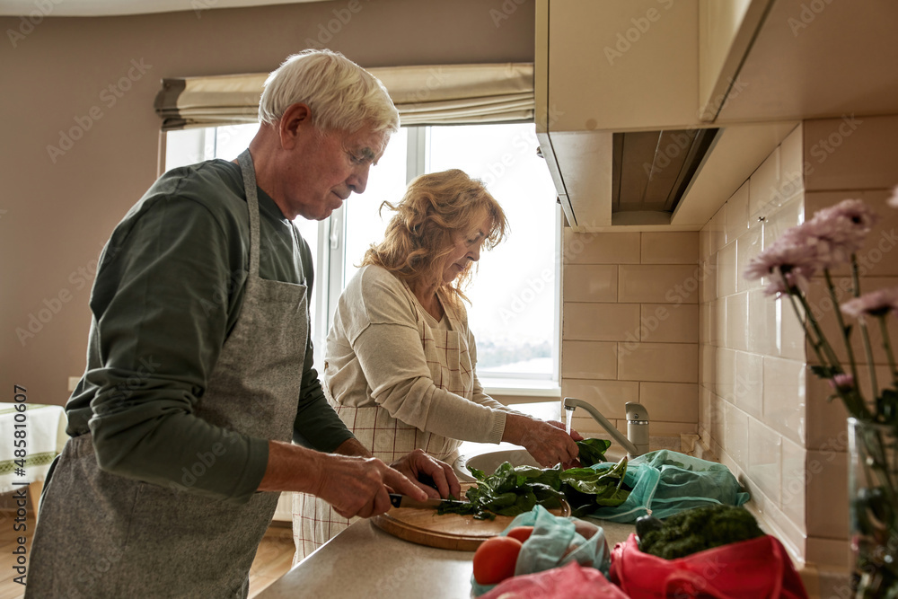 Mature couple cooking salad at home kitchen Mature couple cooking salad at home kitchen