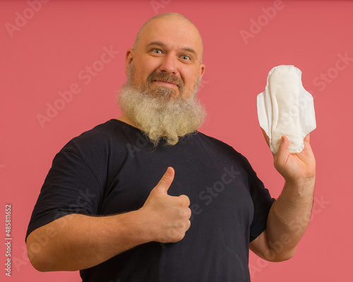 bearded man showing thumb up and holding feminine sanitary napkin on pink background
