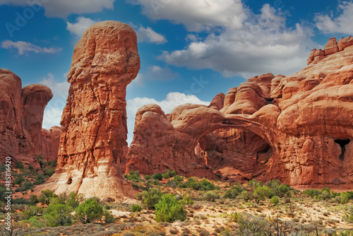 Wallpaper Mural View on funny eroded red rugged sandstone formation with stone pillar and natural arch in dry environment against blue sky with cumulus clouds - Penis rock,  Arches national park, Utah Torontodigital.ca