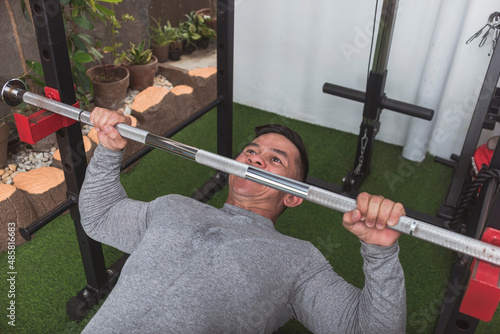Tablou pe pânză A fit asian guy performs a set of bodyweight inverted rows
