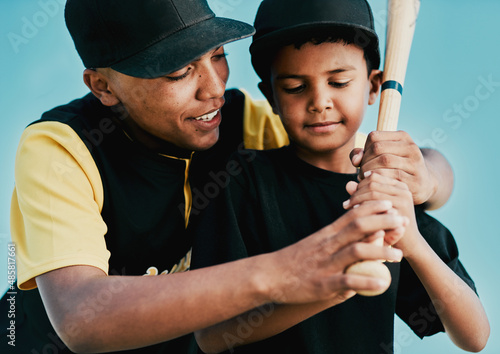 Im training him to be a great player. Shot of a young baseball player showing a little boy how to play.