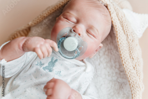Принти на полотні Reborn a boy doll with a pacifier sleeps in a knitted beige envelope