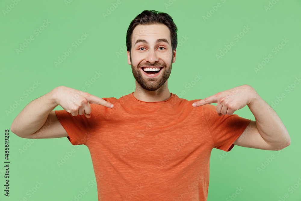 Young surprised exultant fun cool amazed man 20s in casual orange t-shirt point index finger on himself isolated on plain pastel light green color background studio portrait. People lifestyle concept. Young surprised exultant fun cool amazed man 20s in casual orange t-shirt point index finger on himself isolated on plain pastel light green color background studio portrait. People lifestyle concept.