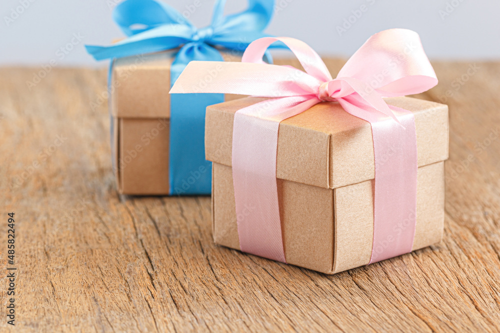 Obraz premium Gift box with ribbon bow on brown wood background