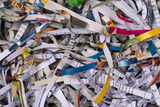 Full frame macro shot of colorful shredded strips of paper with text on it