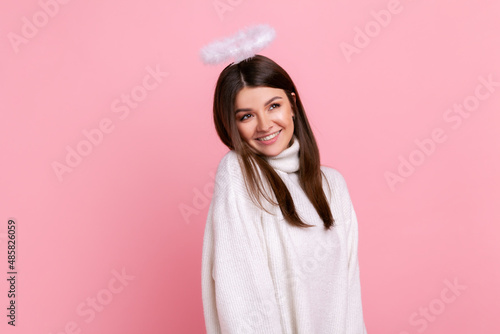 Billede på lærred Attractive brunette angelic woman with nimb over head, looking away with dreamy facial expression, wearing white casual style sweater
