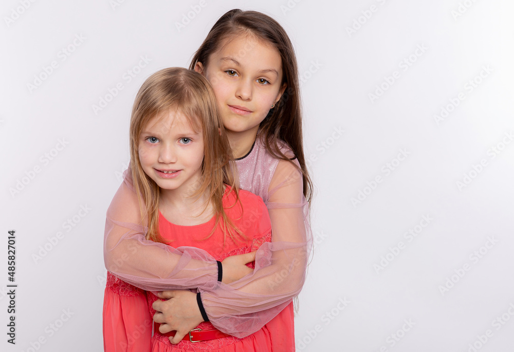Two happy best friends or sisters kid girls hugging. Together having fun and posing emotional on white background, happy smiling, friendship and relationship lifestyle people concept Two happy best friends or sisters kid girls hugging. Together having fun and posing emotional on white background, happy smiling, friendship and relationship lifestyle people concept