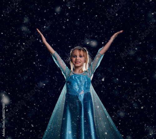 Young girl snow princess. Mystery fantasy girl in blue lush dress. Black art background winter frozen and snow. photo