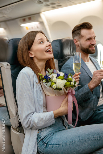 Cheerful woman and man drinking champagne in airplane